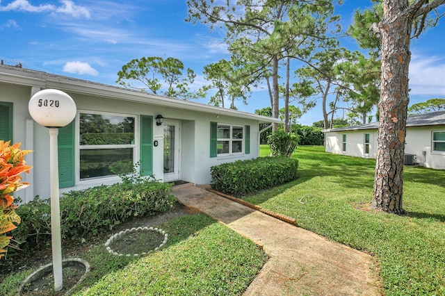 view of front facade featuring a front lawn, cooling unit, and stucco siding