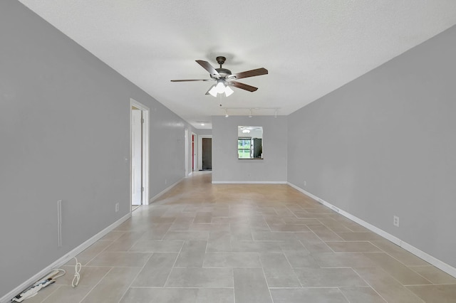 tiled empty room with track lighting, ceiling fan, and a textured ceiling