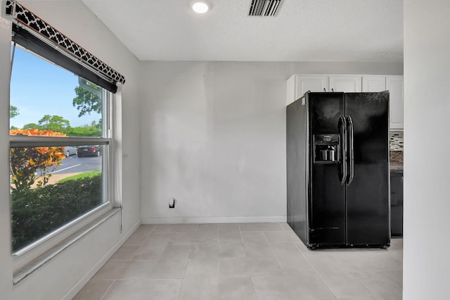 kitchen with white cabinetry, black fridge with ice dispenser, a textured ceiling, and light tile patterned floors