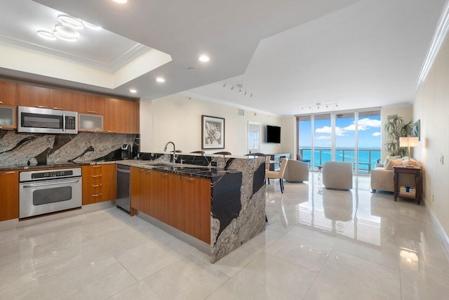 kitchen featuring backsplash, stainless steel appliances, sink, kitchen peninsula, and dark stone counters