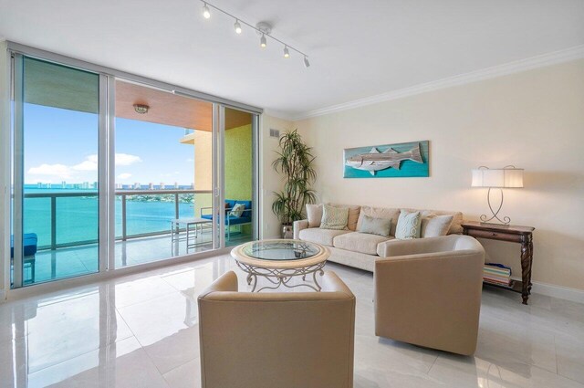 tiled living room with track lighting, ornamental molding, expansive windows, and a water view