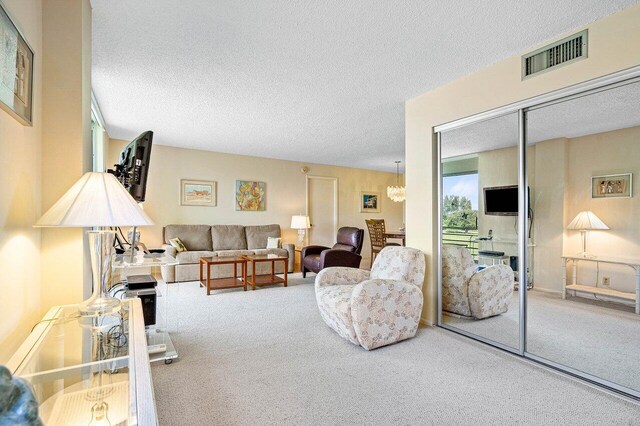 carpeted living room with a textured ceiling and a notable chandelier