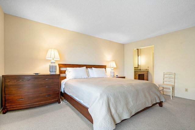 bedroom with a textured ceiling, light carpet, and ensuite bath