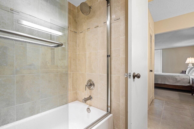 bathroom featuring a textured ceiling, enclosed tub / shower combo, and tile patterned flooring