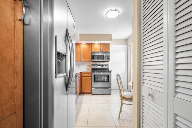 kitchen with light tile patterned floors, appliances with stainless steel finishes, and decorative backsplash