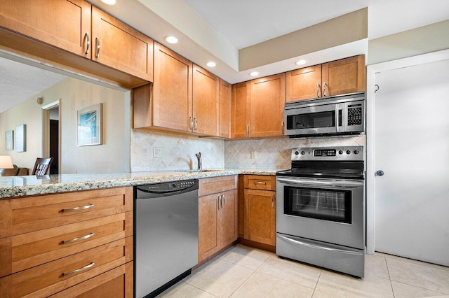 kitchen with light stone counters, light tile patterned floors, appliances with stainless steel finishes, and tasteful backsplash