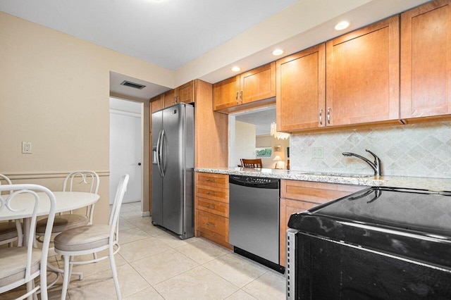 kitchen with light tile patterned floors, tasteful backsplash, stainless steel appliances, sink, and light stone counters