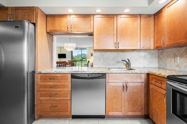 kitchen featuring light stone counters, stainless steel appliances, sink, light tile patterned flooring, and decorative backsplash