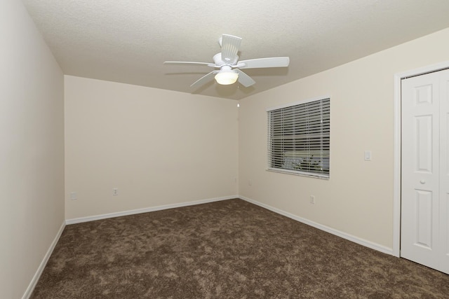 spare room with ceiling fan, dark carpet, and a textured ceiling