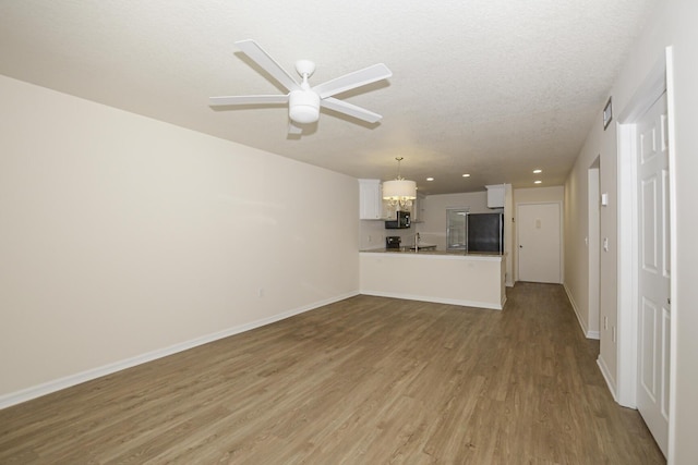 unfurnished living room featuring a textured ceiling, ceiling fan, light hardwood / wood-style floors, and sink