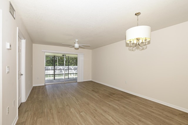 empty room with a textured ceiling, ceiling fan with notable chandelier, and hardwood / wood-style flooring