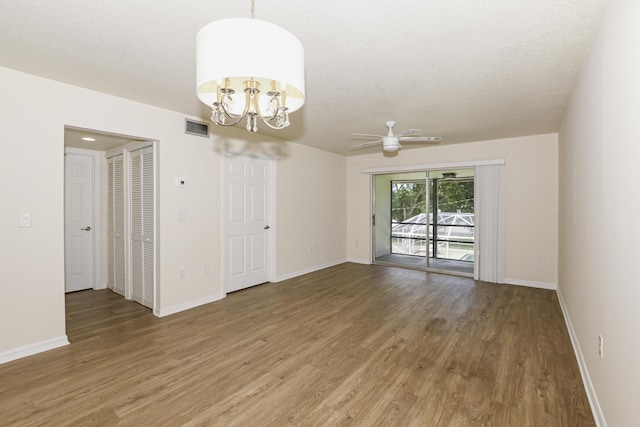 spare room with ceiling fan with notable chandelier, wood-type flooring, and a textured ceiling