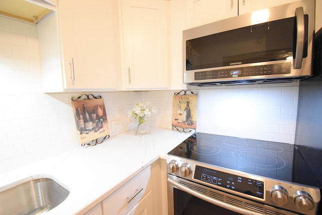 kitchen with backsplash, stove, and white cabinetry