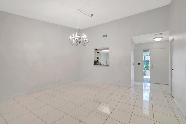 tiled empty room featuring a chandelier