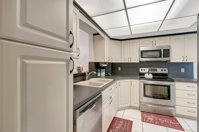 kitchen featuring backsplash, white cabinetry, sink, light tile patterned flooring, and stainless steel appliances