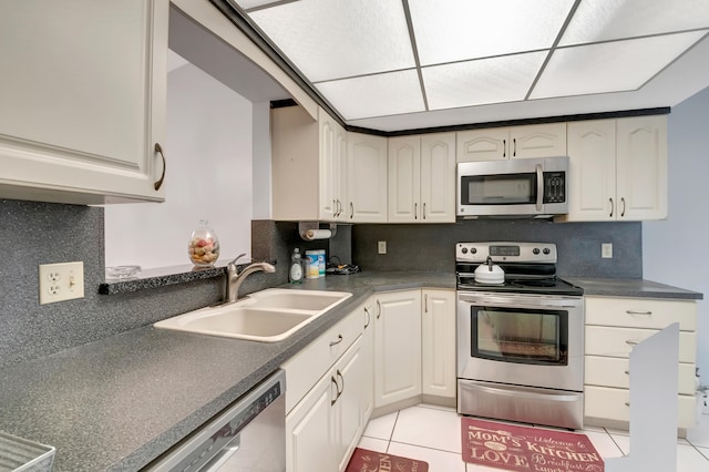 kitchen featuring light tile patterned flooring, sink, appliances with stainless steel finishes, tasteful backsplash, and white cabinets