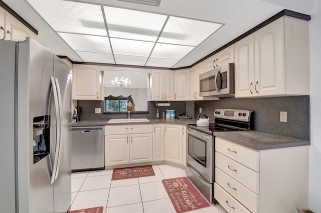 kitchen with appliances with stainless steel finishes, decorative backsplash, a chandelier, sink, and light tile patterned flooring