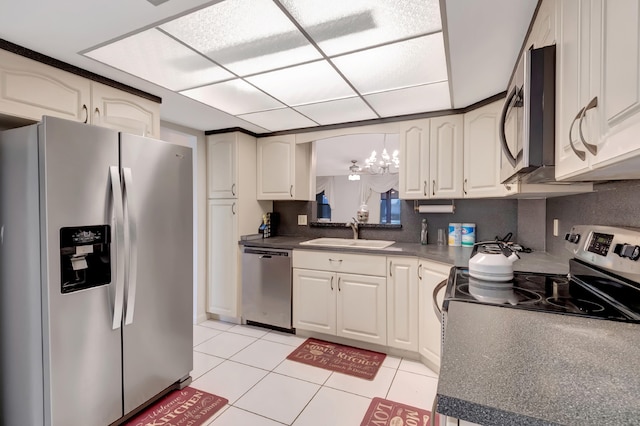 kitchen featuring appliances with stainless steel finishes, light tile patterned flooring, sink, and white cabinetry