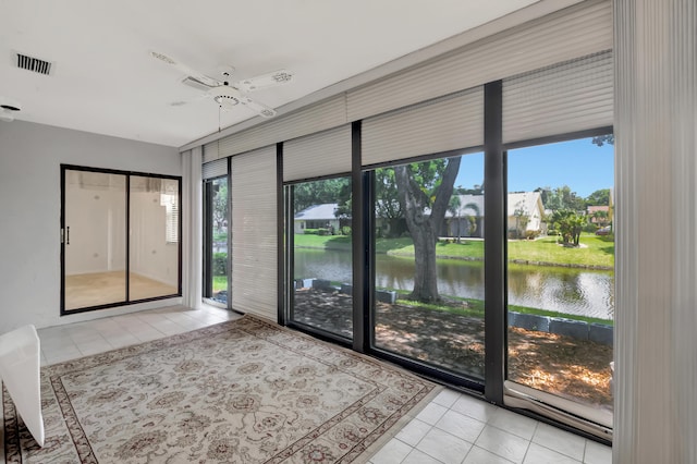 unfurnished sunroom featuring ceiling fan, a water view, and a healthy amount of sunlight