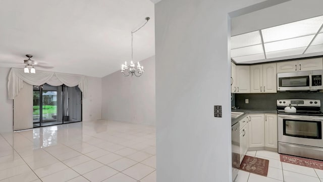 kitchen featuring ceiling fan with notable chandelier, stainless steel appliances, light tile patterned flooring, and backsplash