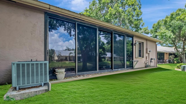 view of side of home featuring cooling unit and a lawn