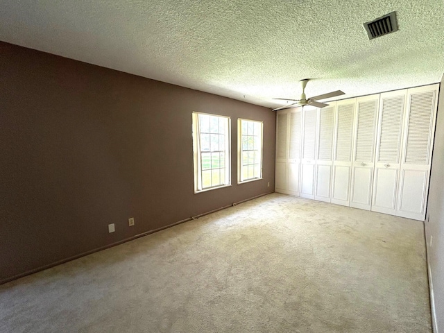 unfurnished bedroom featuring a textured ceiling, ceiling fan, and light carpet