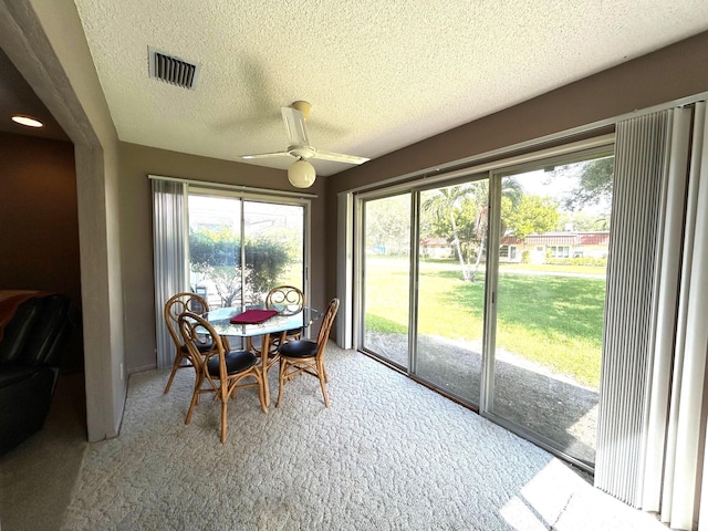 carpeted dining area with a textured ceiling and ceiling fan