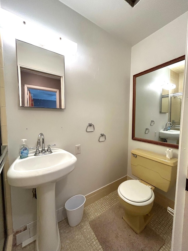 bathroom with toilet, sink, and tile patterned flooring