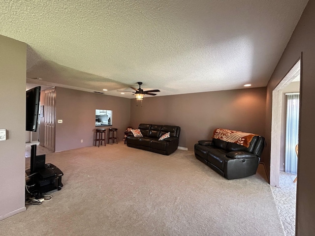 living room featuring ceiling fan, light carpet, and a textured ceiling