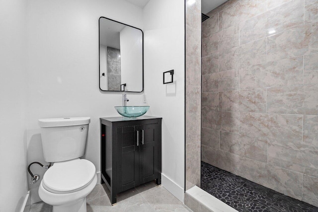 bathroom featuring tile patterned flooring, vanity, toilet, and tiled shower