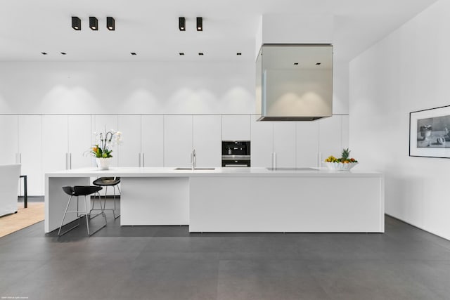 kitchen with range hood, white cabinets, sink, black appliances, and a kitchen breakfast bar