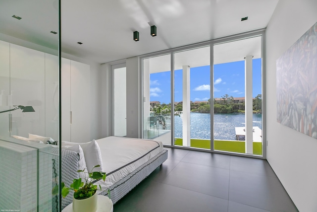 unfurnished bedroom with a water view, a wall of windows, and access to exterior