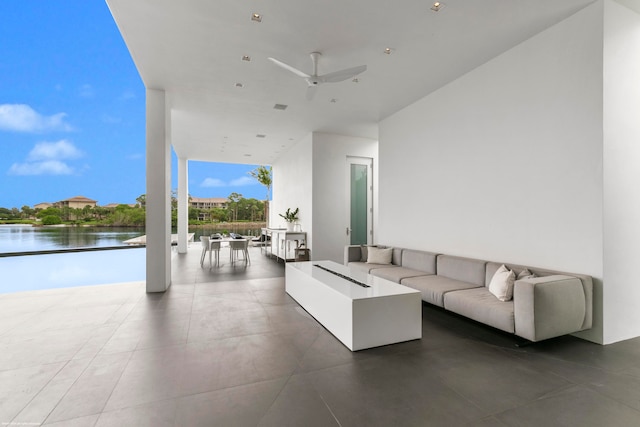 unfurnished living room featuring floor to ceiling windows, ceiling fan, and a water view