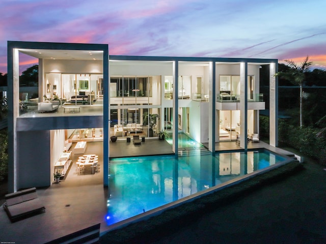 pool at dusk with a patio area