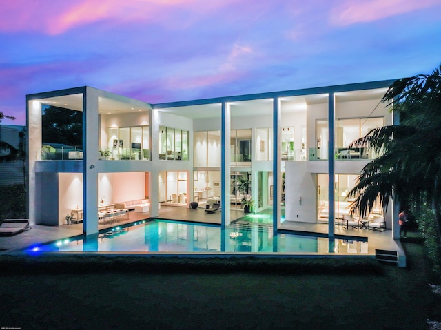 pool at dusk with a patio area