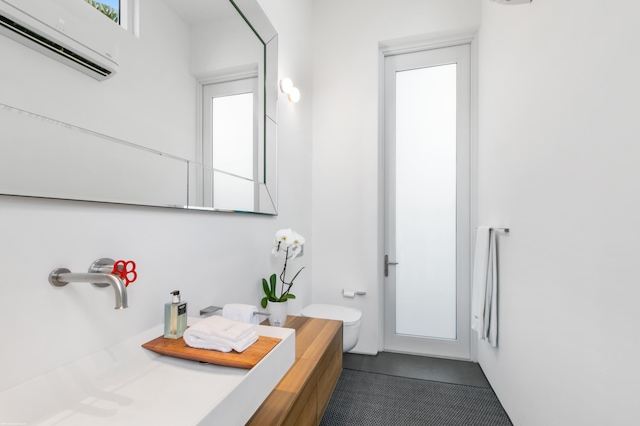 bathroom with vanity, toilet, and a wall unit AC