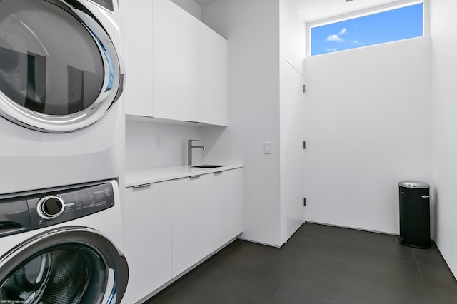 clothes washing area featuring cabinets, sink, and stacked washer / drying machine