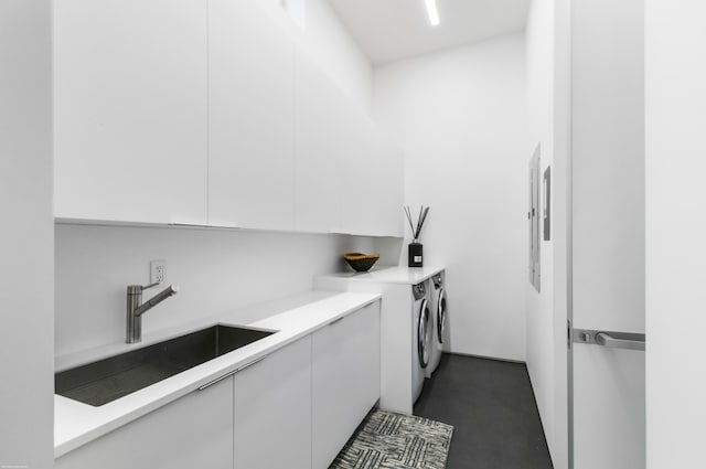 clothes washing area featuring washing machine and clothes dryer, cabinets, and sink