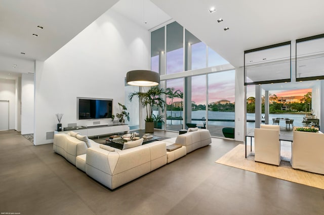 living room featuring a high ceiling, expansive windows, and concrete flooring