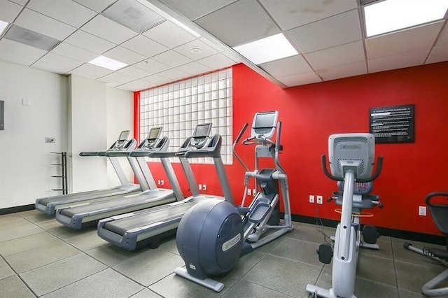 workout area featuring a drop ceiling and baseboards