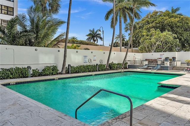 community pool with a patio and fence