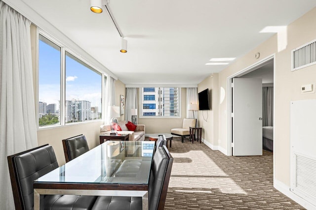 dining area with rail lighting, visible vents, baseboards, and a city view