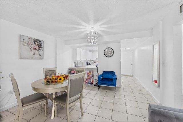 tiled dining area with a chandelier and a textured ceiling