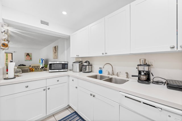 kitchen featuring light tile patterned floors, white cabinetry, sink, and white dishwasher