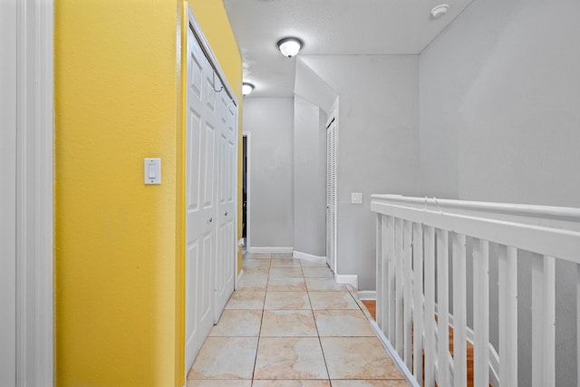 corridor with a textured ceiling and light tile patterned flooring