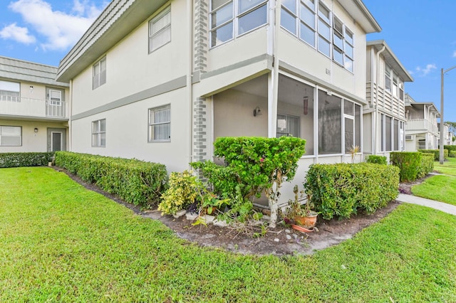 view of side of home featuring a yard and a balcony