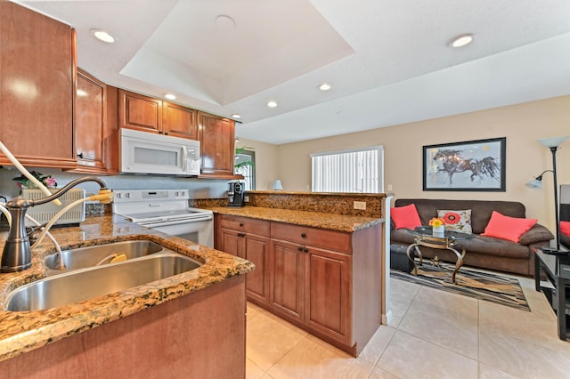 262 Monaco F, Delray Beach, FL 33446 - kitchen featuring white appliances, a sink, brown cabinets, a tray ceiling, and light tile patterned floors