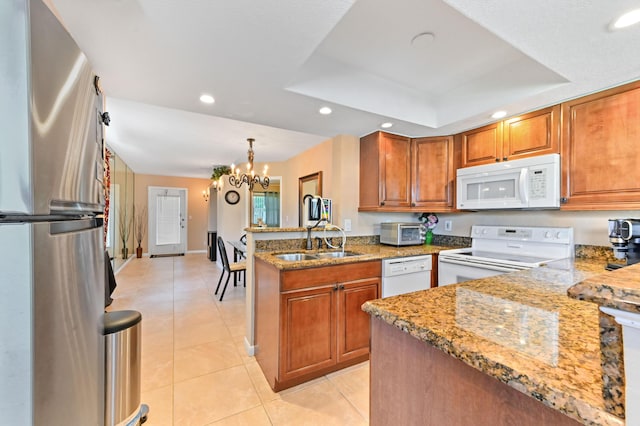 262 Monaco F, Delray Beach, FL 33446 - kitchen with white appliances, a sink, a peninsula, brown cabinets, and a tray ceiling