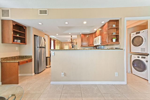 262 Monaco F, Delray Beach, FL 33446 - kitchen with open shelves, freestanding refrigerator, white microwave, stacked washer / drying machine, and brown cabinets