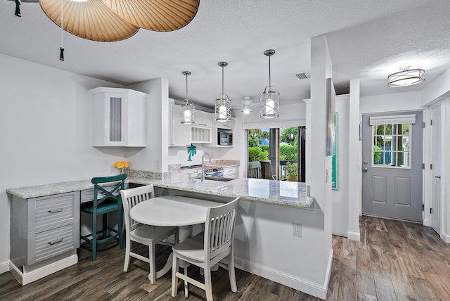 kitchen featuring white cabinetry, hanging light fixtures, kitchen peninsula, and dark hardwood / wood-style flooring